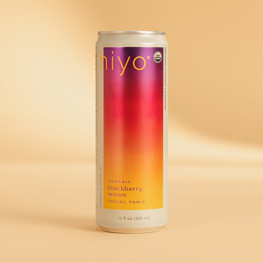 Niyo brand organic blackberry lemon social tonic in a 12 fl oz aluminum can with gradient purple to yellow label on beige bac
