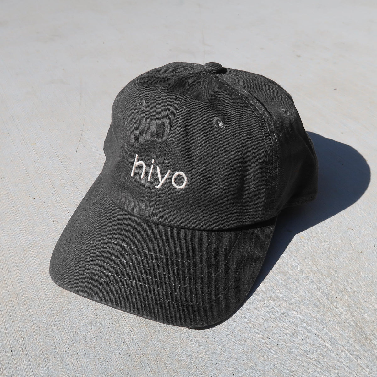 a charcoal dad hat featuring the hiyo logo embroidered in cream.