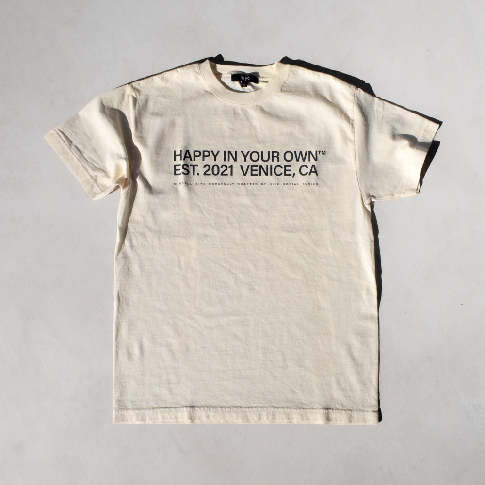 Cream colored short-sleeve t-shirt with black text reading "Happy in Your Own Est. 2021 Venice, CA" on the front.
