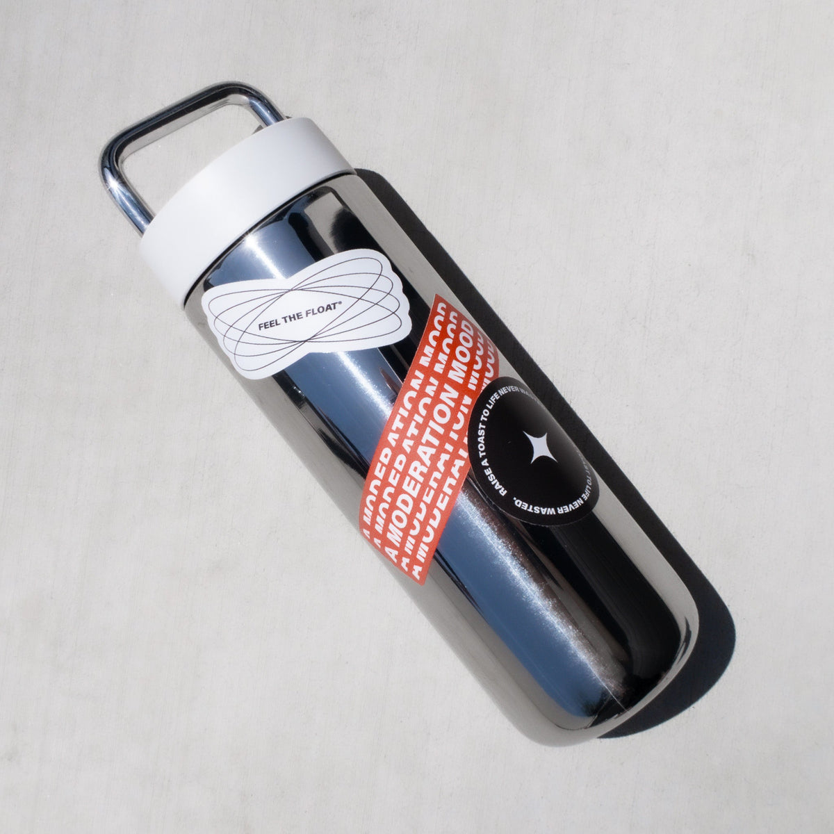 Black water bottle with white cap wrapped with red and white sticker sheet featuring "Feel the Float" text.