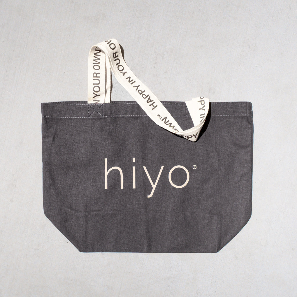 Charcoal gray tote bag with "hiyo" logo and text printed handles reading "what's inside matters."