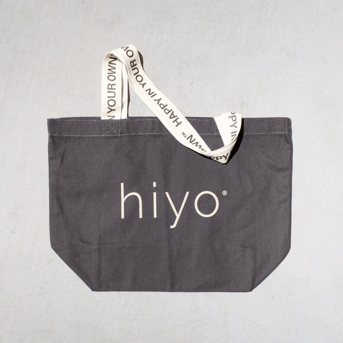 Charcoal gray tote bag with "hiyo" logo and text printed handles reading "what's inside matters."