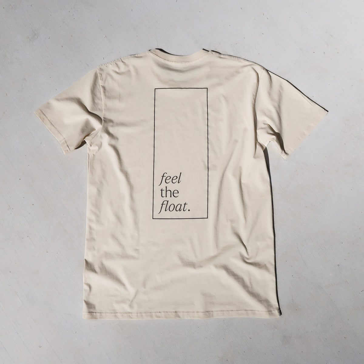 a cream t-shirt with 'feel the float' inside a rectangle printed across the full back.