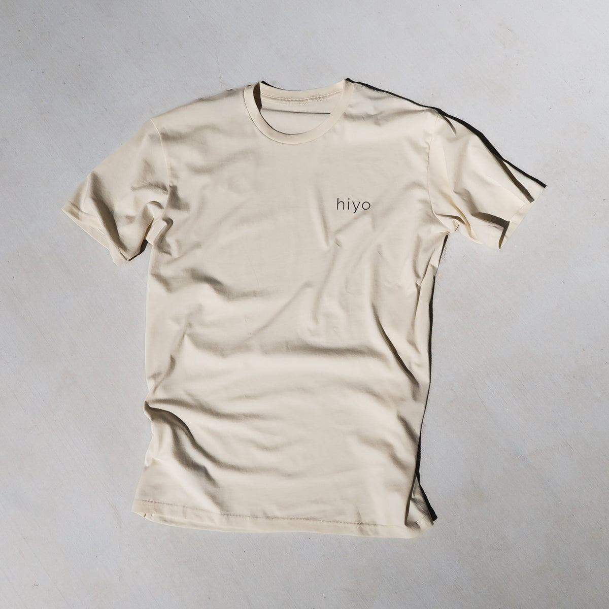 a cream t-shirt with the hiyo logo printed in charcoal on the front left chest.