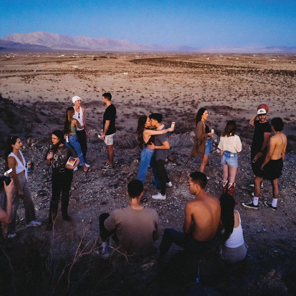 friends enjoying hiyo while talking, embracing, and enjoying the view of a desert at sunset.