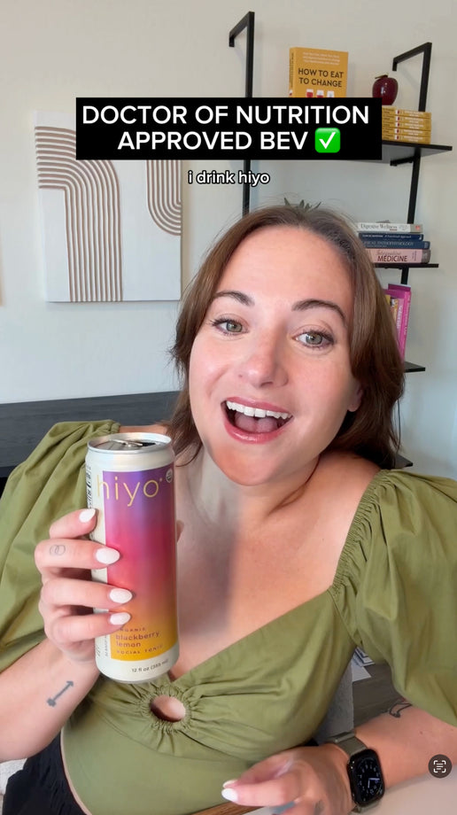a doctor of nutrition prepares a fresh apple in a kitchen while a can of hiyo social tonic sits on the counter. the video then shows her working at a desk with hiyo beside her as on-screen text discusses supporting calm and relaxation, highlighting the beverage as part of her daily routine.